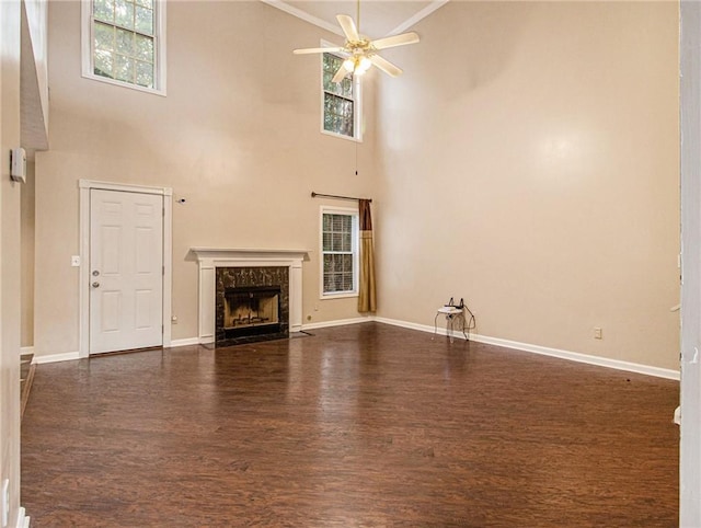 unfurnished living room with ceiling fan, a fireplace, dark wood-type flooring, and a high ceiling