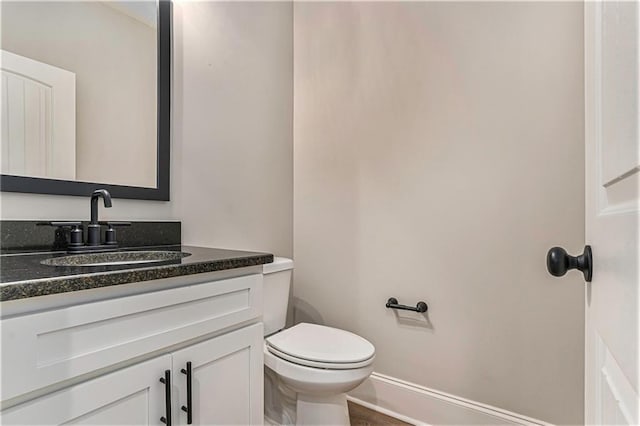 bathroom with toilet, baseboards, and vanity