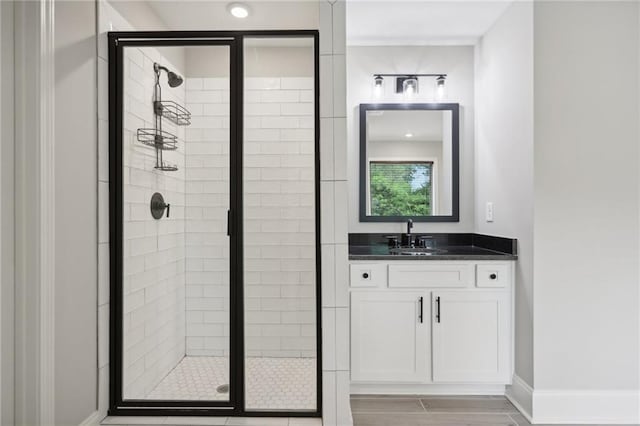 full bath with baseboards, a shower stall, and vanity