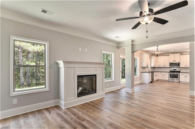 unfurnished living room with visible vents, baseboards, crown molding, light wood-style floors, and a sink