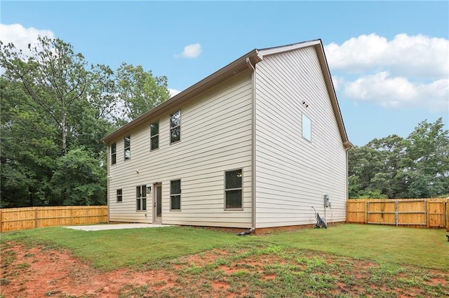 back of property with a fenced backyard, a yard, and a patio