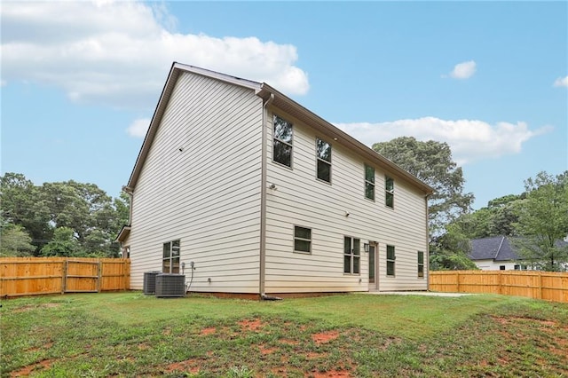 rear view of house with cooling unit, a fenced backyard, and a lawn