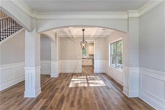 unfurnished dining area with arched walkways, beamed ceiling, coffered ceiling, and dark wood finished floors