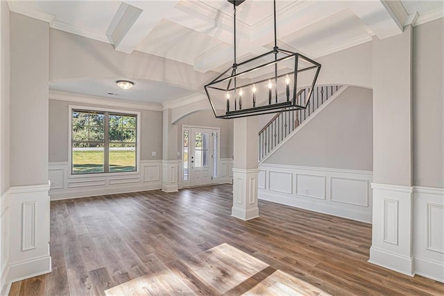 unfurnished living room featuring dark wood-type flooring, arched walkways, beamed ceiling, and stairs