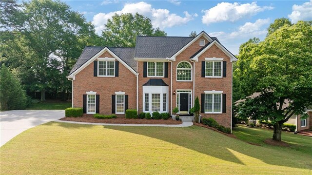 colonial house featuring a front lawn and brick siding