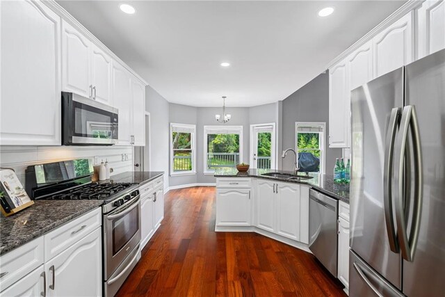 kitchen with a peninsula, recessed lighting, white cabinetry, a sink, and stainless steel appliances