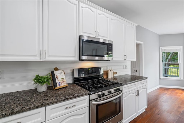 kitchen featuring dark wood finished floors, dark stone countertops, white cabinets, and stainless steel appliances