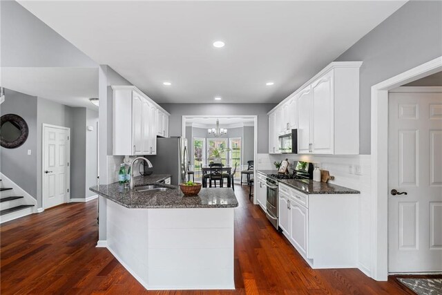 kitchen with a sink, dark stone countertops, appliances with stainless steel finishes, and a chandelier