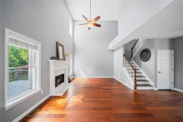unfurnished living room featuring a high end fireplace, ceiling fan, stairway, and wood finished floors