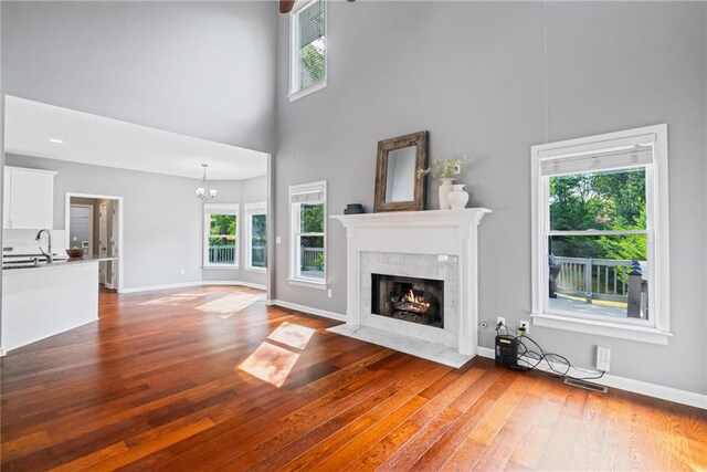 unfurnished living room featuring a high end fireplace, a high ceiling, wood finished floors, and a wealth of natural light