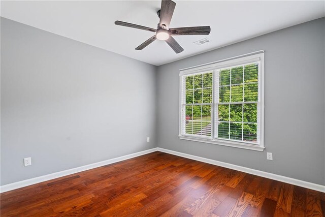 spare room with baseboards, visible vents, ceiling fan, and wood finished floors