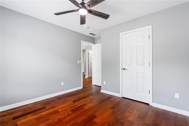 unfurnished bedroom with a ceiling fan, baseboards, visible vents, and dark wood finished floors
