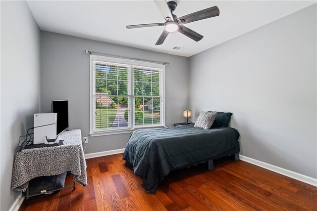 bedroom featuring ceiling fan, baseboards, visible vents, and wood finished floors