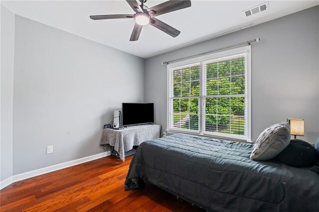 bedroom featuring visible vents, baseboards, ceiling fan, and wood finished floors
