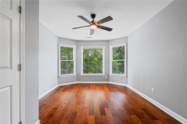 spare room with baseboards, dark wood finished floors, and ceiling fan