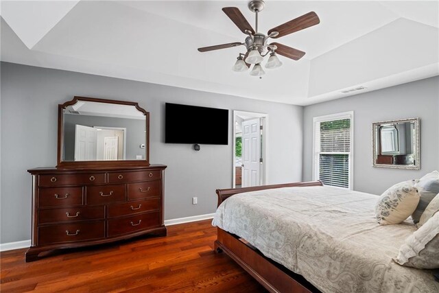 bedroom with dark wood-style flooring, baseboards, visible vents, and a raised ceiling