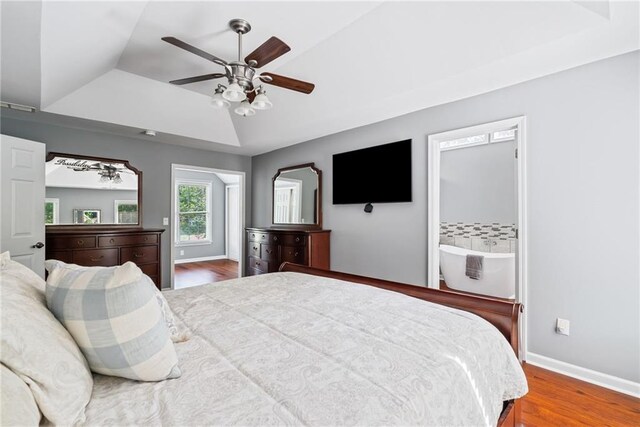bedroom featuring ceiling fan, a raised ceiling, baseboards, and wood finished floors