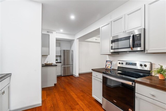 kitchen with appliances with stainless steel finishes, wooden counters, recessed lighting, visible vents, and dark wood-style floors
