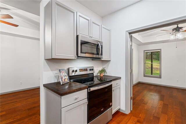 kitchen featuring appliances with stainless steel finishes, ceiling fan, baseboards, and dark wood-style floors
