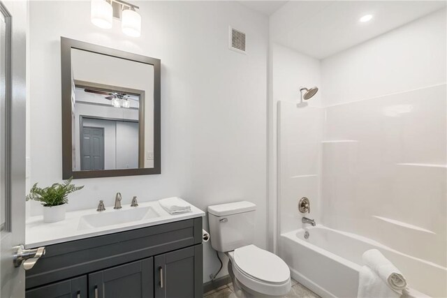 bathroom featuring vanity, visible vents, toilet, baseboards, and shower / washtub combination
