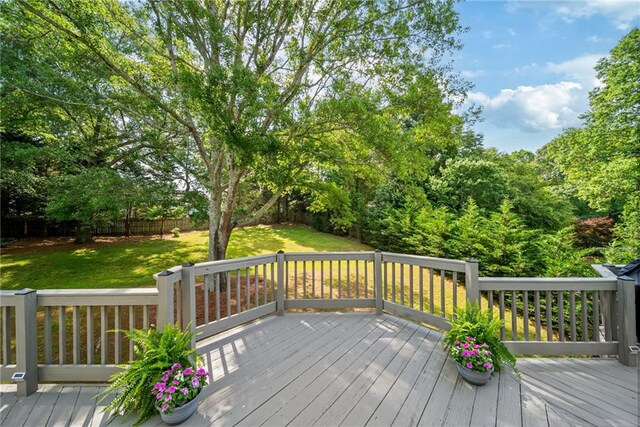 wooden terrace featuring a fenced backyard and a yard