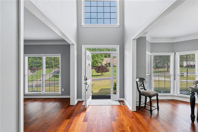 foyer entrance featuring crown molding, baseboards, visible vents, and wood finished floors