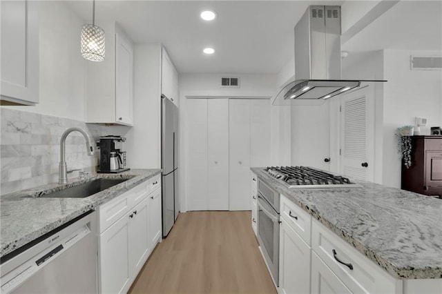 kitchen featuring island exhaust hood, decorative light fixtures, sink, stainless steel appliances, and white cabinetry