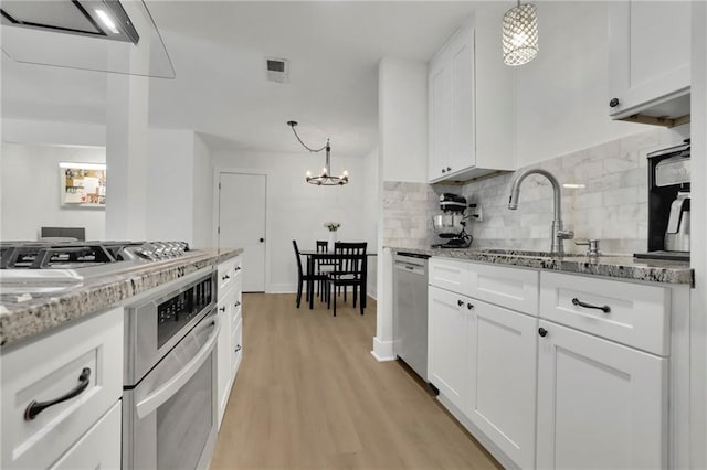 kitchen with light hardwood / wood-style flooring, decorative light fixtures, sink, stainless steel appliances, and white cabinets