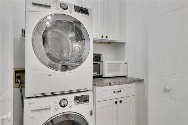 laundry area with stacked washer and dryer and cabinets