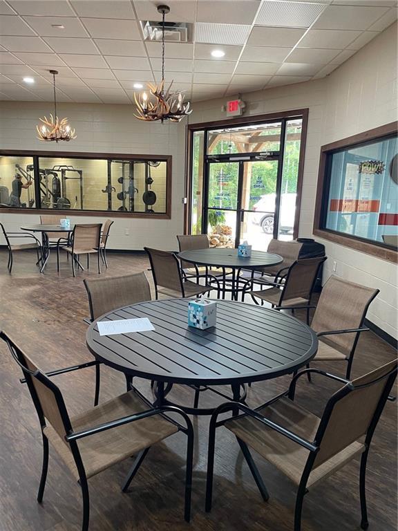 dining space featuring an inviting chandelier, wood-type flooring, and a drop ceiling