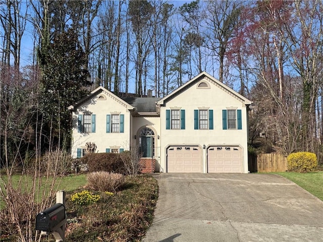 split foyer home with driveway, a garage, fence, and stucco siding