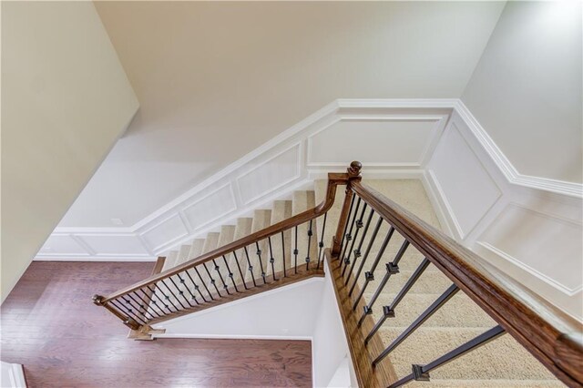 stairs with wood finished floors and a decorative wall