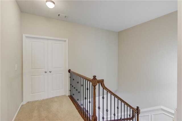 corridor featuring visible vents, carpet floors, and an upstairs landing