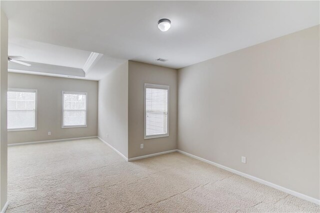 empty room featuring a ceiling fan, carpet flooring, visible vents, and baseboards