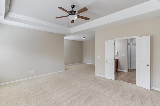 unfurnished bedroom featuring ceiling fan, carpet flooring, baseboards, ornamental molding, and a tray ceiling