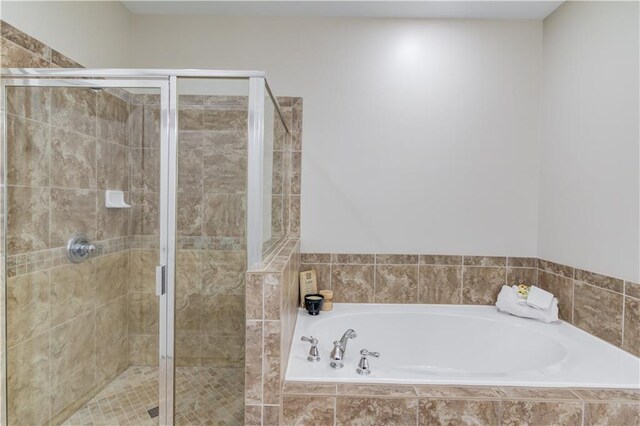 bathroom featuring a stall shower and a bath