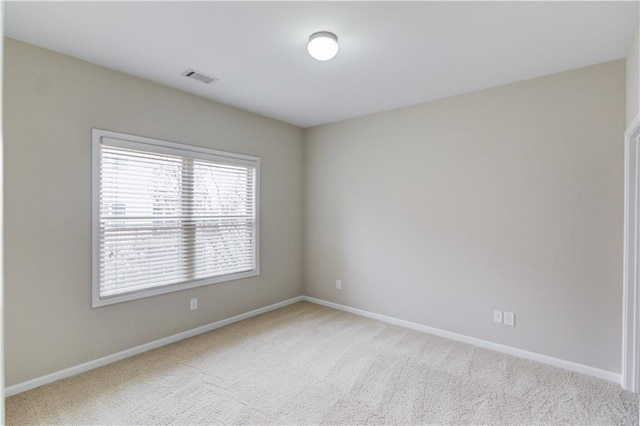 carpeted spare room with visible vents and baseboards