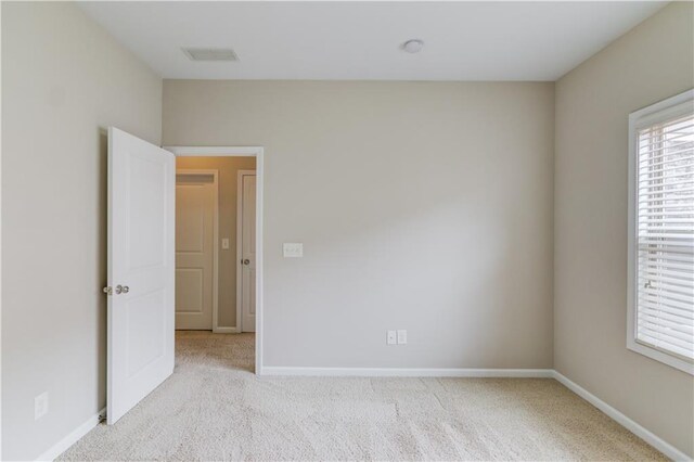 unfurnished room with carpet flooring, visible vents, and baseboards