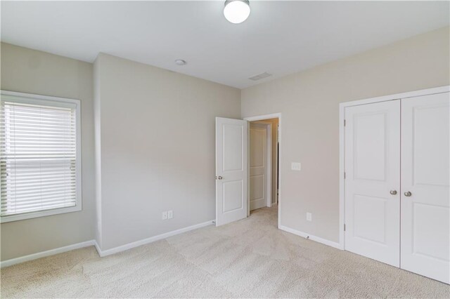 unfurnished bedroom with carpet floors, visible vents, baseboards, and a closet