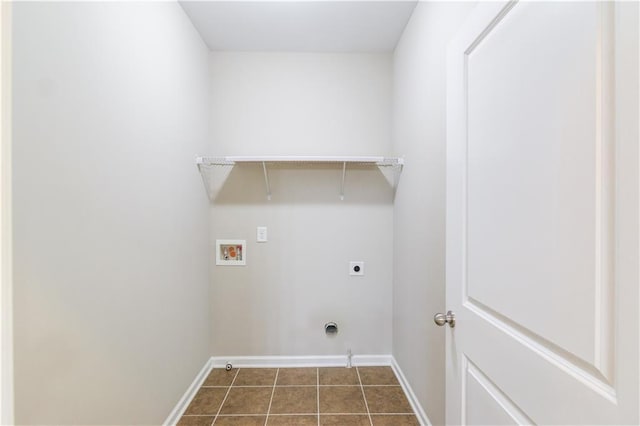 clothes washing area with washer hookup, electric dryer hookup, laundry area, dark tile patterned floors, and baseboards