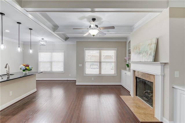 unfurnished living room featuring a healthy amount of sunlight, a sink, dark wood finished floors, and crown molding