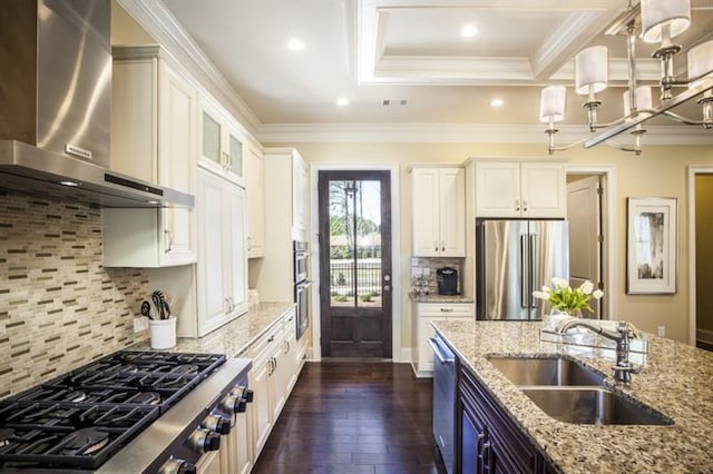 kitchen with appliances with stainless steel finishes, light stone counters, sink, wall chimney range hood, and white cabinetry