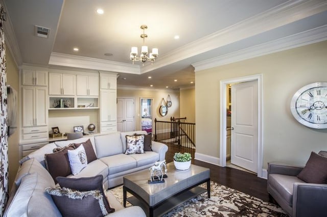 living room with dark hardwood / wood-style flooring, crown molding, a tray ceiling, and a chandelier