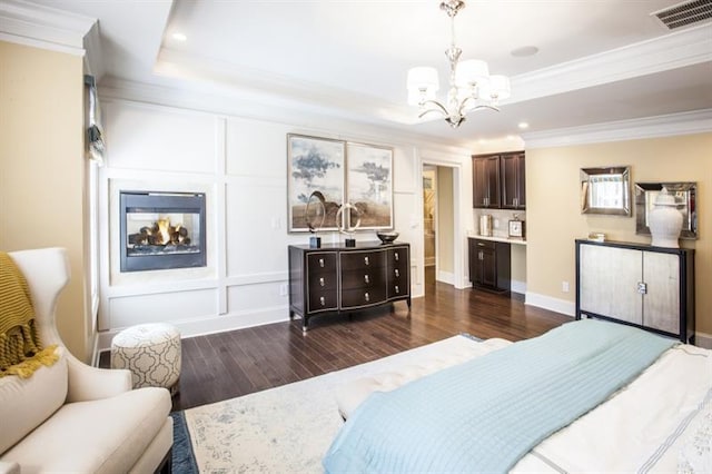 bedroom with a notable chandelier, dark hardwood / wood-style floors, a raised ceiling, and ornamental molding