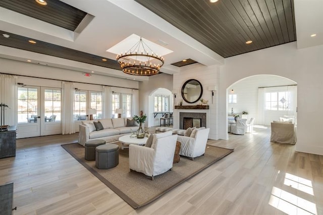 living room featuring french doors, light wood-type flooring, a fireplace, wood ceiling, and a chandelier