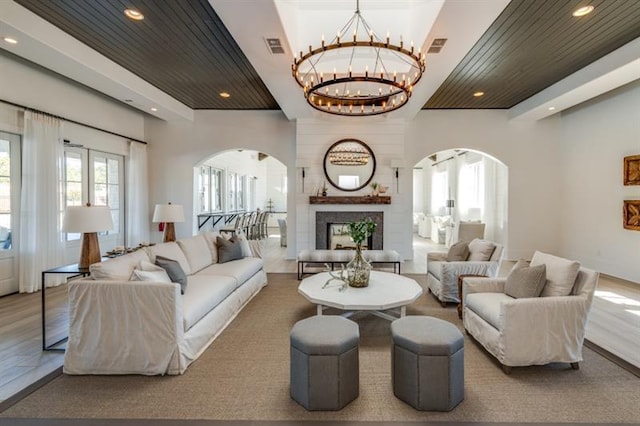 living room featuring hardwood / wood-style flooring, a notable chandelier, a large fireplace, and wooden ceiling