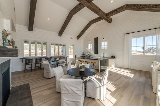 dining room with beam ceiling, high vaulted ceiling, and a wealth of natural light