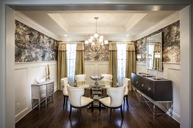 dining area with a raised ceiling, an inviting chandelier, ornamental molding, and hardwood / wood-style flooring