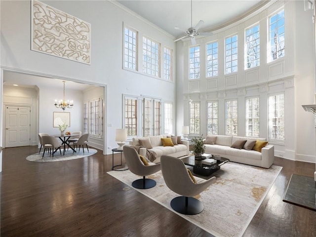 living room featuring crown molding, a healthy amount of sunlight, and a towering ceiling