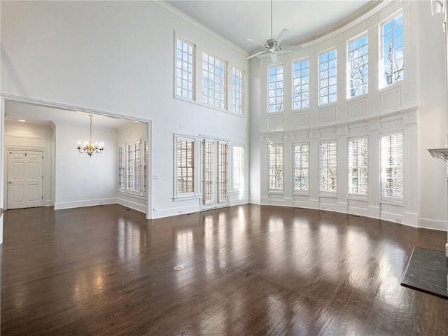 unfurnished living room with a towering ceiling, ornamental molding, and ceiling fan with notable chandelier